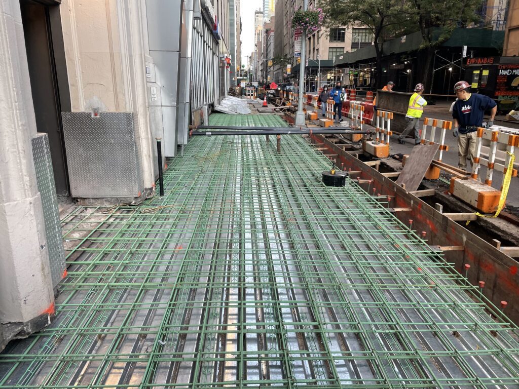 A Street Under Construction With Visible Metal Rebar Grid Structures Laid Down on the Road in Preparation for Concrete Pouring.